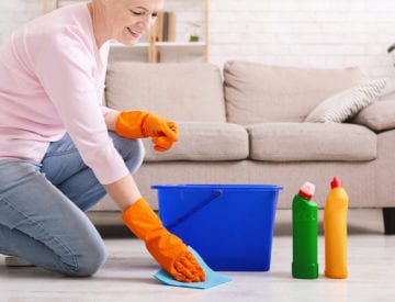 Senior woman spring cleans floor.